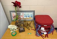 Overview showing framed print, cushions stack, artificial flower, brass sleigh, lantern, planter, tape