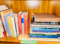 Shelf with standing hardcover and paperback books showing spines