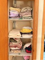 Full view of cabinet with stacked bedding and table linens