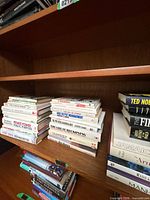 Three stacks and one upright row of assorted hardcovers and paperbacks on shelf