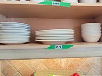 Stack of dinner plates, rimmed soup plates and bowls on shelf