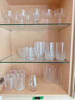 Cabinet view showing all three shelves with plastic tumblers, crystal stemmed glasses, highballs and stemless tumblers