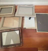 Five assorted frames laid out on floor showing variety of styles and finishes