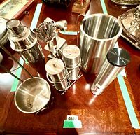 Full view of assorted stainless bar tools and accessories on table