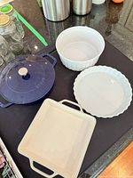 Top view of Staub cocotte with lid, three white ceramic bakers