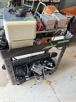 Full view of two-shelf black plastic cart loaded with electronics (not included)