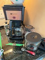 Front view of Bunn coffee maker with attached carafe, french press and accessories visible