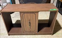 Front view of wood laminate cabinet stand showing center door and open side compartments