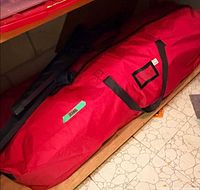 Red storage bag containing disassembled tree under shelf