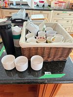 Overall lot with basket of mugs, travel mug, stacked tumblers, white cups