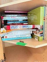 Stack of cookbooks on shelf showing multiple titles
