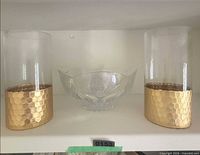 Crystal bowl flanked by two gold-base glass candleholders on shelf