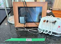 Digital photo frame, power adapter, hand mixer with beaters displayed on countertop