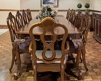 Overall view of extended dining table showing chairs for scale, parquetry top and carved back chair in foreground