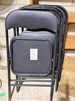 Stack of four black folding chairs