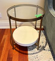 Full view of the table showing glass top, brass frame, white shelf