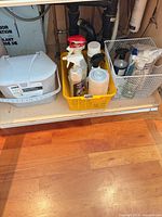 Under-sink view of whole lot: cleaners in yellow basket and white wire bin, Oxo compost bin