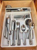Overview of drawer showing entire stainless steel cutlery set in white organizer