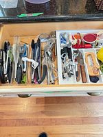 Full drawer view showing left clear organizer and right white organizer filled with assorted utensils