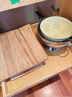 Maple cutting board and nested colanders inside cabinet