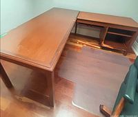 Full view of L-shaped desk showing glass top and wood finish