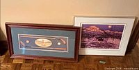 Both framed prints leaning against wall
