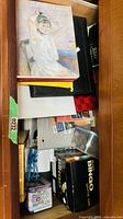 Drawer showing Berthe Morisot book, bingo game, binders, cables