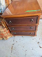 Full view of wooden nightstand front and side showing three drawers and hardware