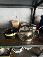 Group of cookware on shelf: bundt pan, canister, lidded stainless pans