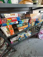 Full shelving unit showing stacked boxed puzzles on two shelves