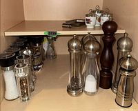 Front view showing multiple acrylic and stainless grinders and dark wood mill
