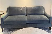 Front view of grey-blue velvet sofa showing cushions and legs