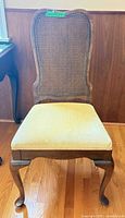 Front view showing entire chair, wood frame, cane back, cream seat