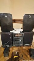 Front view of JVC stereo main unit with four speakers, cables and power adapter on table