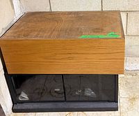 Front view of cabinet showing wood veneer top, black base, glass doors