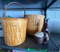 Tall handled basket, large round basket, brown rabbit figurine with small basket on metal shelf