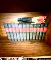 All nine hardcover encyclopedia volumes and stacked pamphlets on shelf