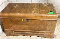 Front view of wood trunk showing lock, veneer pattern and base molding