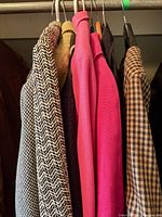 Six jackets of varying colours and patterns hanging on closet rod