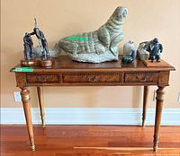Full front view of wooden console table with three drawers and turned legs