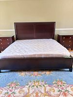 Full view of wood king bed frame with mattress and cover