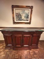 Front view of carved wooden sideboard with black stone top