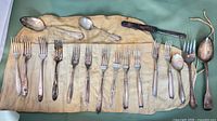 Full layout of 18 mixed silver-plated pieces on cloth roll