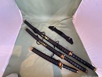 Overview of three swords with scabbards and wall mount bracket