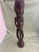Front view of carved wooden female figure standing on integral base
