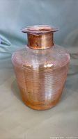 Full view of ribbed amber-pink iridescent glass vase with copper collar