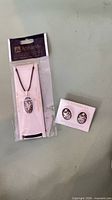 Necklace pendant in sealed sleeve beside carded stud earrings
