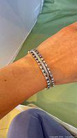 Bracelet worn on wrist showing overall double-row design of blue rhinestones and silver-tone links