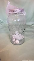 Front view of clear embossed glass beverage dispenser with spigot parts visible inside