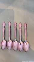 Five teaspoons front view displaying ornate handles and bowls